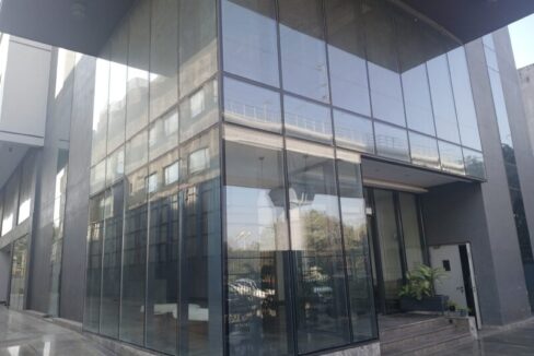 Modern glass-front corporate office building in Mohan Cooperative Industrial Estate.